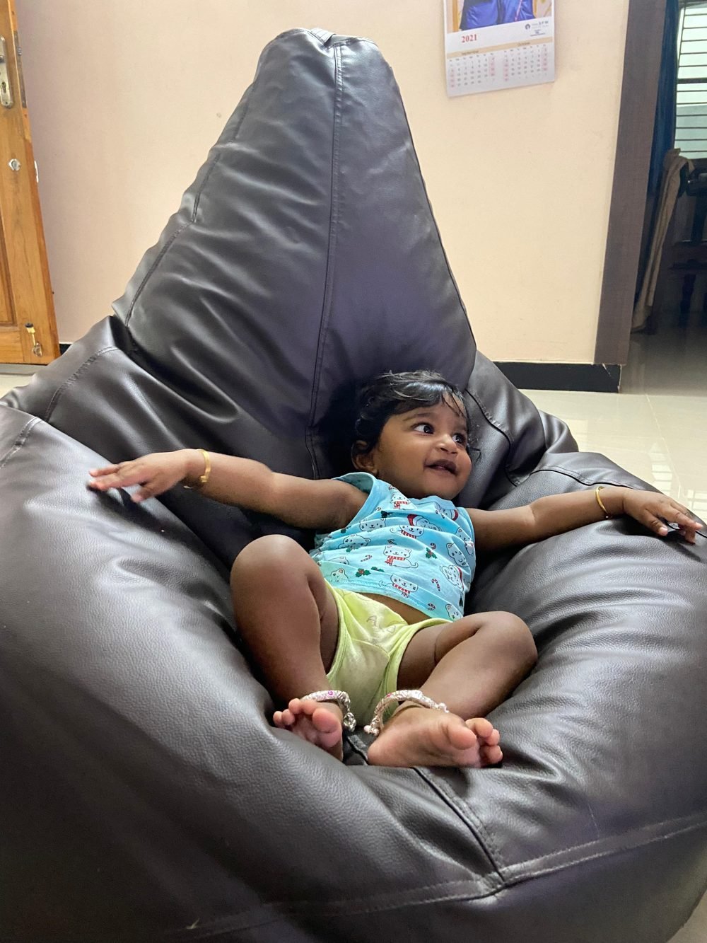 Dhuruvan smiling, arms spread wide on a big brown bean bag